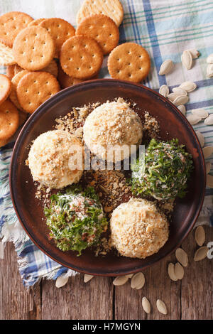 Cottage cheese sfere con cracker, erbe e semi di zucca close-up su una piastra. vista verticale da sopra Foto Stock