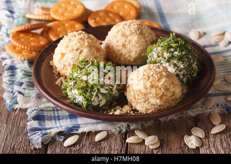 Alimentare utile: palline di formaggio con cracker, erbe e semi di zucca close-up su una piastra orizzontale. Foto Stock