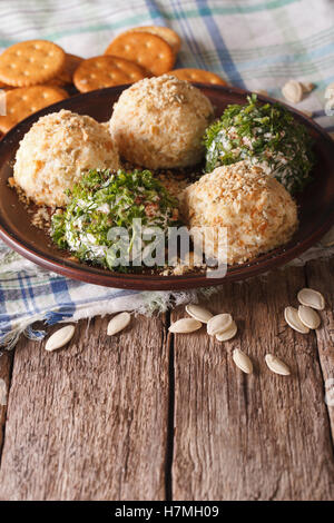 Formaggio di capra sfere con cracker, erbe e semi di zucca close-up su una piastra. In verticale Foto Stock