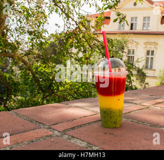 Cocktail frullato in un materiale plastico trasparente di tazza di frutti di bosco freschi, kiwi, arance e fragole. Foto Stock