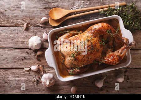 Cibo francese: pollo con quaranta spicchi di aglio nel piatto di cottura e ingredienti di close-up sul tavolo. vista orizzontale f Foto Stock