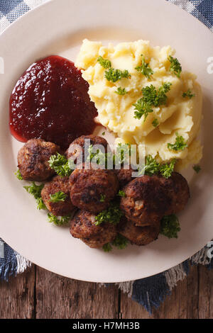 La cucina svedese: polpette, lingonberry sugo con patate guarnite su una piastra di close-up. vista verticale da sopra Foto Stock