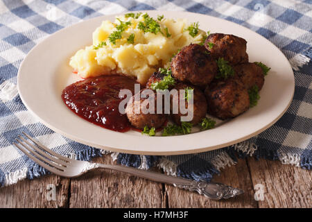 La cucina svedese: polpette, lingonberry sugo con patate guarnite su una piastra di close-up orizzontale. Foto Stock