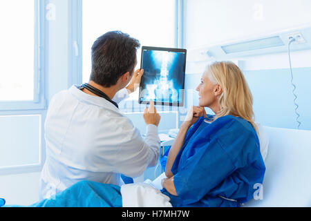 Medico mostrando Xray per un senior paziente in ospedale Foto Stock