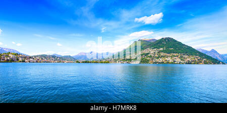 Lago di Lugano paesaggio panoramico. Città, lago di acqua, cielo blu e montagne. Ticino, Svizzera o dalla Svizzera e Europa. Foto Stock