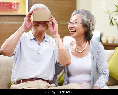 Senior asian giovane stupito dalla tecnologia mentre cercando occhiali vr Foto Stock