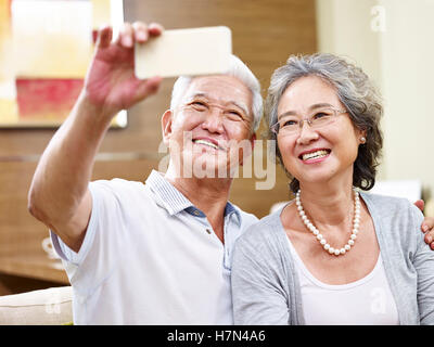Senior asian giovane prendendo un selfie a casa utilizzando il cellulare Foto Stock
