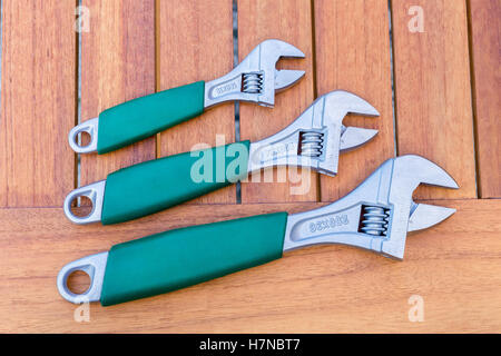Tre chiavi regolabili di diverse dimensioni che giace sul tavolo di legno Foto Stock