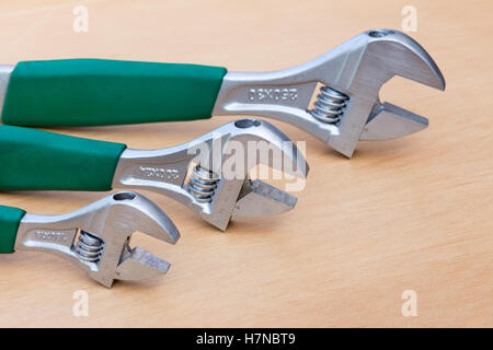 Tre chiavi regolabili di dimensioni diverse in posizione eretta su legno Foto Stock