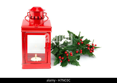 Lanterna rossa con tealight holly ciuffi e bacche rosse isolato su sfondo bianco Foto Stock