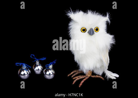 White civetta delle nevi figurine con argento palle di Natale isolato su sfondo nero Foto Stock