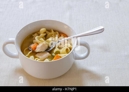 Fatto in casa zuppa di noodle al pollo con le carote e il sedano servito in una ciotola bianco. Foto Stock