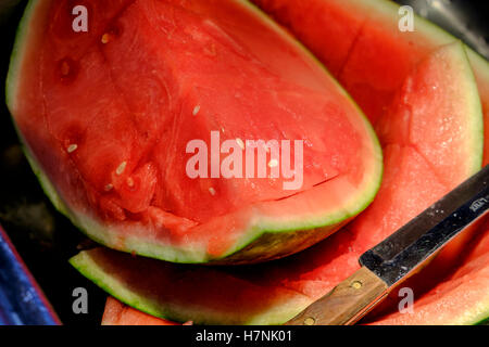 Porzioni di fresca anguria seedless essendo tagliato su un bancone cucina e lavello. Foto Stock