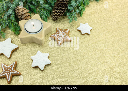 Natale a forma di stella i cookie con candela e Abete rami con rocche su sfondo dorato Foto Stock