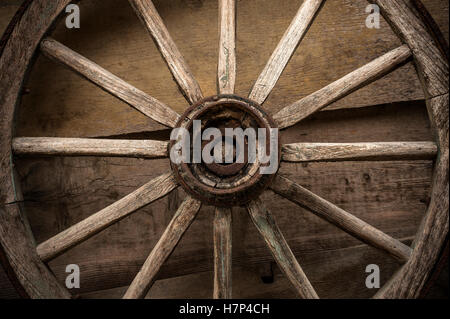 Vecchia ruota di legno usato per il trasporto su una parete in legno. Foto Stock