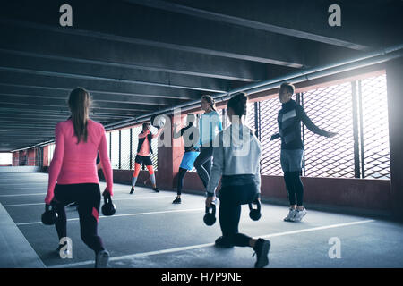 Gruppo di persone che esercitano utilizzando pesi e corde di salto, di indossare abbigliamento sportivo Foto Stock