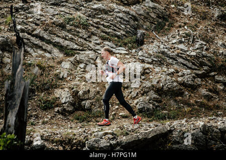 Giovani runner viene eseguito su un sentiero di montagna in pietra di sfondo rocce durante la Crimea maratona di montagna Foto Stock