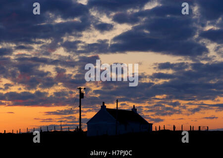 Tramonto dietro un tipico delle Ebridi storia unica home Traigh un Iar Malacleit North Uist Ebridi Esterne della Scozia Foto Stock