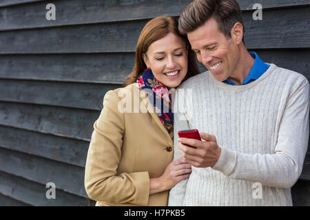 Attraente, di successo e Felice uomo di mezza età e la donna giovane insieme all'esterno tramite telefono cellulare Foto Stock