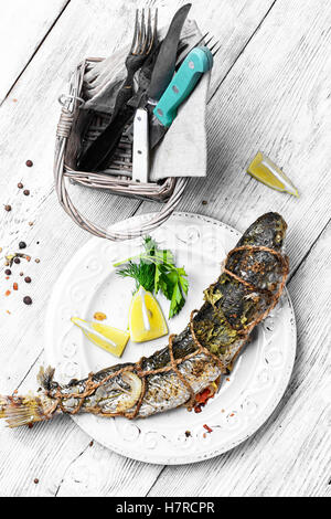 Carcassa intera di pesce alla griglia su piastra di luce su uno sfondo chiaro Foto Stock