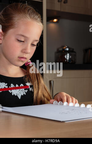 Ragazza giovane svolgendo compiti al tavolo della cucina Foto Stock