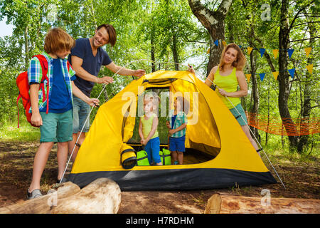 I genitori mettendo a tenda con bambini in viaggio di campeggio Foto Stock