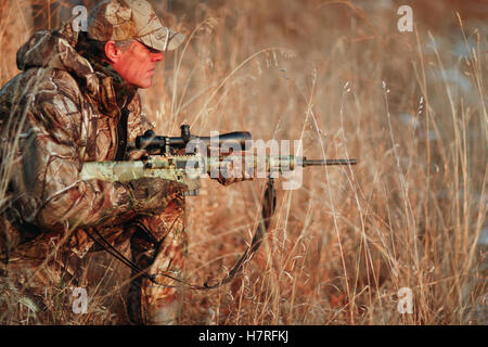 Predator Hunter Stalking in un campo con un fucile Foto Stock