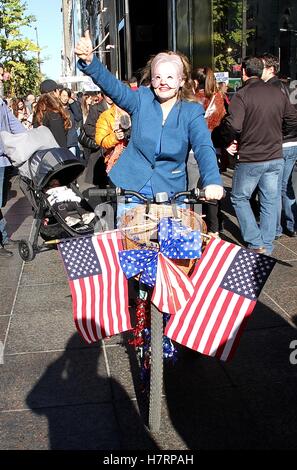 New York, NY, STATI UNITI D'AMERICA. 7 Nov, 2016. Una donna non identificato in un Hillary Clinton costumi dà un pollice in alto come ella corse una bicicletta decorate con bandierine americane passato Trump Tower il giorno prima gli Stati Uniti elezioni presidenziali in New York New York il 7 novembre 2016. © Rainmaker foto/media/punzone Alamy Live News Foto Stock