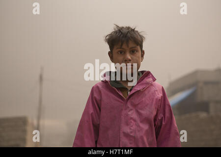 Qayyarah, Niniveh, Iraq. 8 Novembre, 2016. 08/11/2016. Qayyarah, Iraq. Un giovane coperto di olio ragazzo iracheno è visto su una strada piena di fumo in Qayyarah, Iraq. Pozzi di petrolio in e intorno alla città di Qayyarah, Iraq, abbiamo impostato acceso nel Luglio 2016 da uno Stato islamico gli estremisti come l esercito iracheno ha iniziato un offensiva per liberato il paese.Per due mesi i residenti della città hanno vissuto sotto un quasi costante nuvola di fumo, l'unica tregua provenienti quando il vento cambia. Credito: ZUMA Press, Inc./Alamy Live News Foto Stock