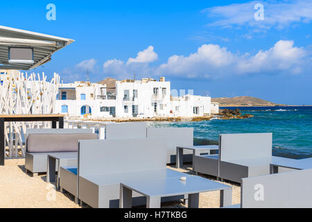 Tabelle di Taverna sulla spiaggia di Naoussa porto di pesca, isola di Paros, Grecia Foto Stock