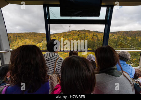 I passeggeri in un cavo auto prendere in autunno colori come il loro approccio alla fine fermare al di sotto di Mt. Asahidake. Foto Stock