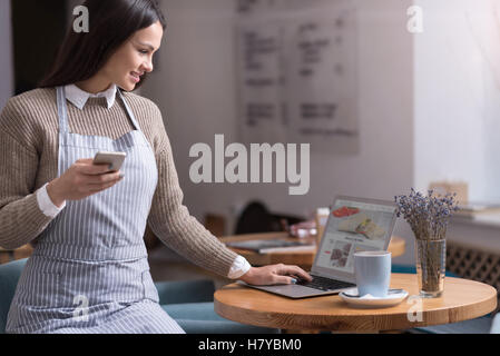 Gioiosa donna sorridente con notebook e cellulare. Foto Stock