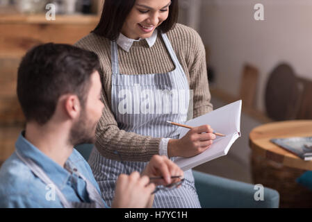 Giovane donna sorridente che mostra note per uomo bello. Foto Stock