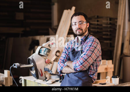 Felice giovane falegname tuttofare in laboratorio, sorridente Foto Stock