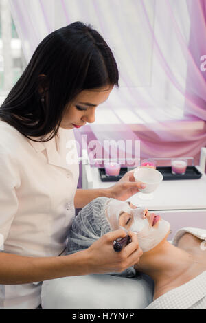 Concetto di Spa. Giovane donna con nutriente maschera facciale nel salone di bellezza Foto Stock