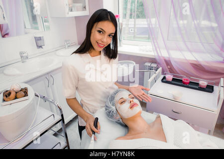 Concetto di Spa. Giovane donna con nutriente maschera facciale nel salone di bellezza Foto Stock