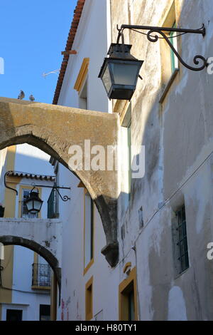 EVORA, PORTOGALLO: Close-up su lampade stradali e archi in una strada stretta Foto Stock