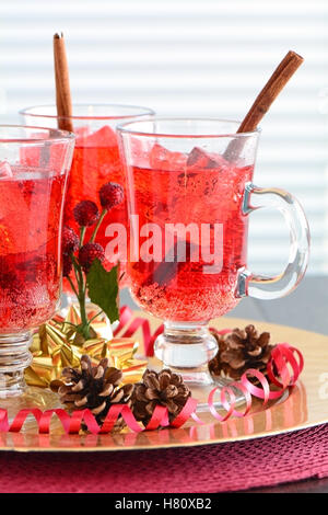 Festive rosso frizzante di soda di mirtillo palustre di bevande con cannella agitare bastoni in rosso e oro accenti a tema. Profondità di campo Foto Stock