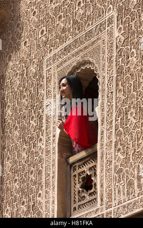 Il Marocco,Marrakech,Ben Youssef Medersa,costruito 1564, donna del peering da una finestra decorata Foto Stock