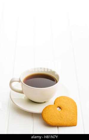 Cuori di panpepato e la tazza di caffè sul tavolo bianco. Foto Stock