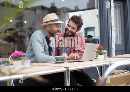 Coppia gay satellitare portatile condivisione in cafe Foto Stock