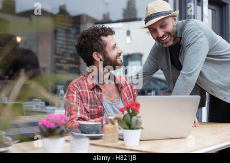 Coppia gay laptop di condivisione in cafe Foto Stock