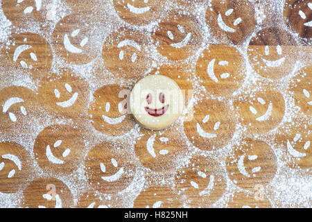 In casa Jammie Dodgers. La faccina sorridente biscotto e zucchero a velo impressioni su legno Foto Stock