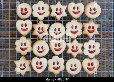 In casa Jammie Dodgers. La faccina sorridente biscotti si affaccia su un filo rack Foto Stock