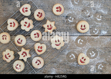 In casa Jammie Dodgers. La faccina sorridente biscotti e zucchero a velo impressioni su legno Foto Stock