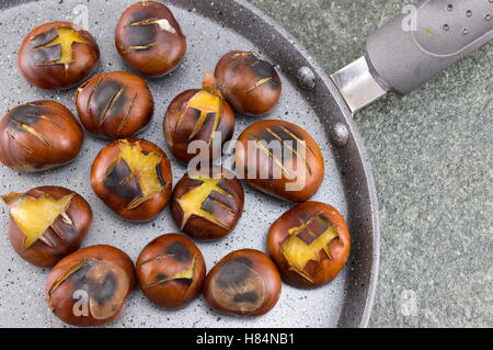 Castagne arrostite su una pietra brasiera Foto Stock