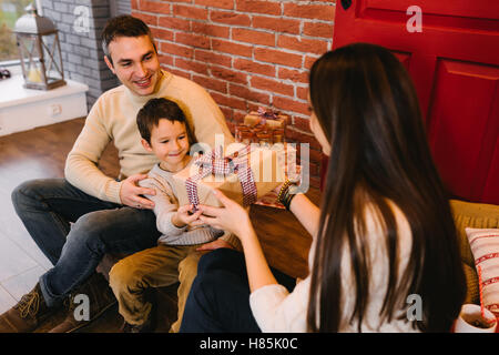 I genitori danno al bambino un regalo per Natale Foto Stock