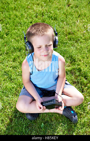 Little Boy con il vecchio lettore di cassette audio e cuffie Foto Stock