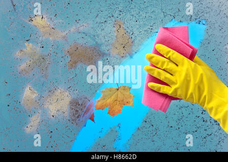 Mano nel guanto di gomma nella finestra di pulizia su un cielo blu sullo sfondo Foto Stock