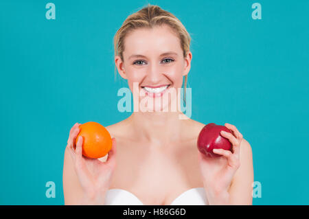 Bella donna azienda apple e orange sorridente Foto Stock